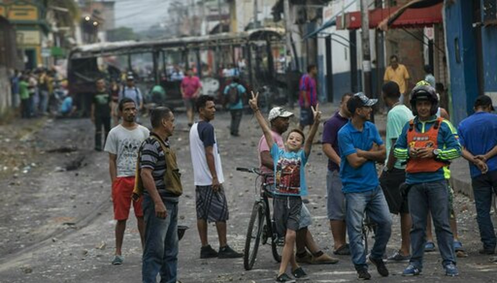 Residents gather in the streets where a public bus was burned during clashes between Bolivarian National Guards and anti-government protesters in Urena, Venezuela, near the border with Colombia, Sunday, Feb. 24, 2019. (AP)