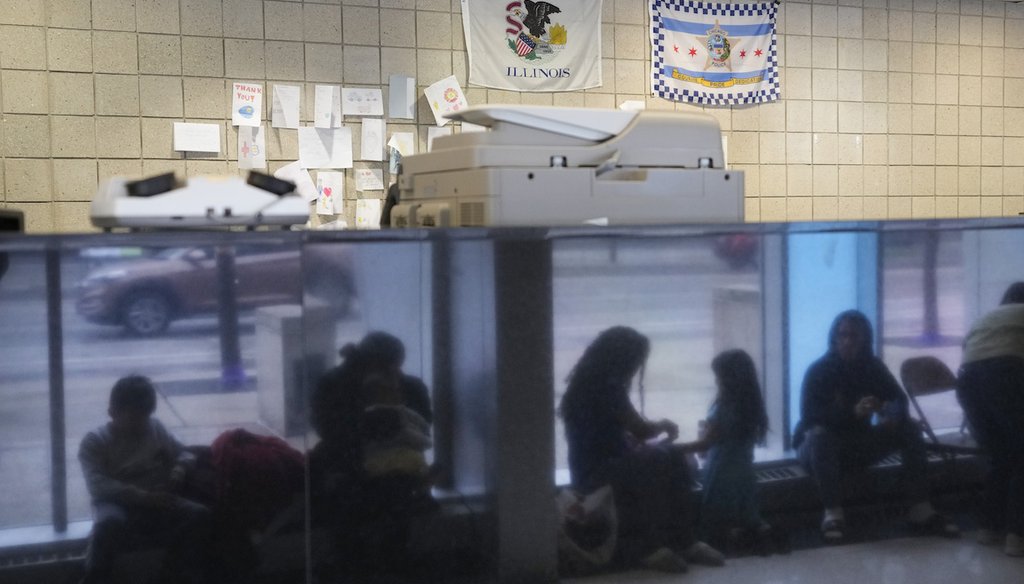 Immigrants from Venezuela are reflected in a marble wall while taking shelter at the Chicago Police Department's 16th District station on May 1, 2023. (AP)