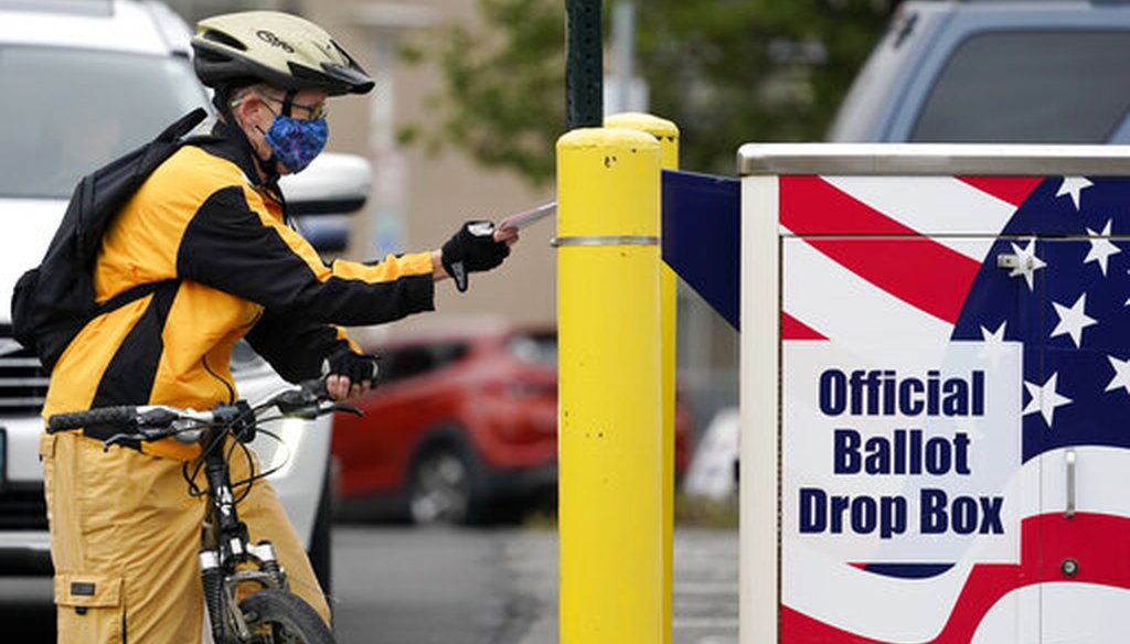 Cyclist Mickey McDiarmid votes by dropping her completed ballot into a ballot drop box Monday, Oct. 19, 2020, in Bellingham, Wash. (AP)