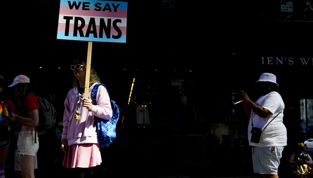 Una persona sostiene un cartel de "We Say Trans" mientras espera a que comience el desfile anual del Orgullo de Seattle, 25 de junio de 2023 (AP)