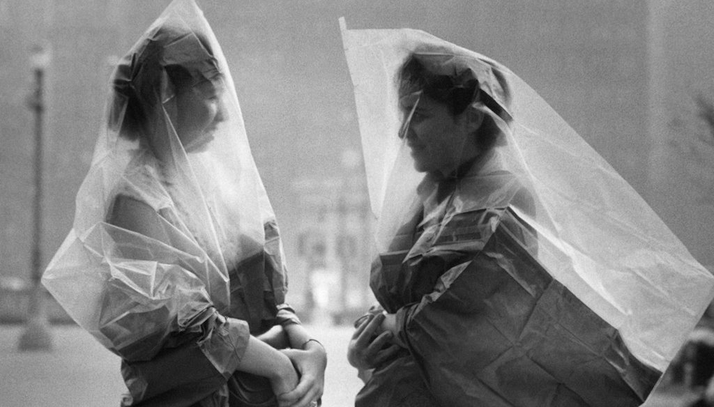 War surplus gas capes are used by Meriel Bush, left, and Ruth Neuer, in an attempt to dodge the eye-stinging effects of a low-hanging smog and smoke in Philadelphia in 1953. Some social media posts incorrectly said this was taken in 1918. (AP)