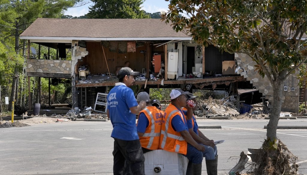 Workers helping with clean up efforts stop for lunch under the shade of a tree as a building destroyed by Hurricane Helene is seen in the background Oct. 5, 2024, in Newport, Tenn. (AP)