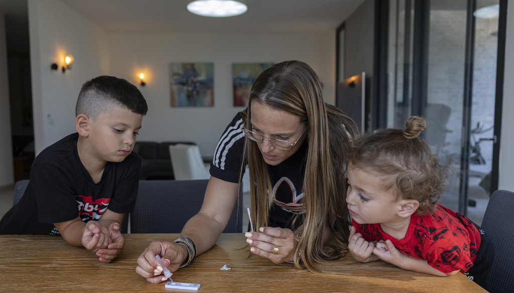 Hila Bohadana drips a solution onto a COVID-19 Antigen Self Test kit after taking a sample from her son, Ori, 10, ahead of the first day of school, at their home in Moshav Kochav Michael near Ashkelon, Israel, Aug. 31, 2021. (AP)