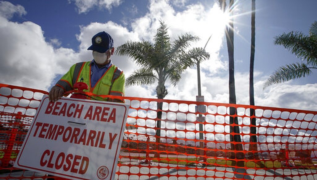 A city worker puts up signs to close the "Wedge" area of the beach in Newport Beach, Calif., Friday, April 10, 2020. (AP)