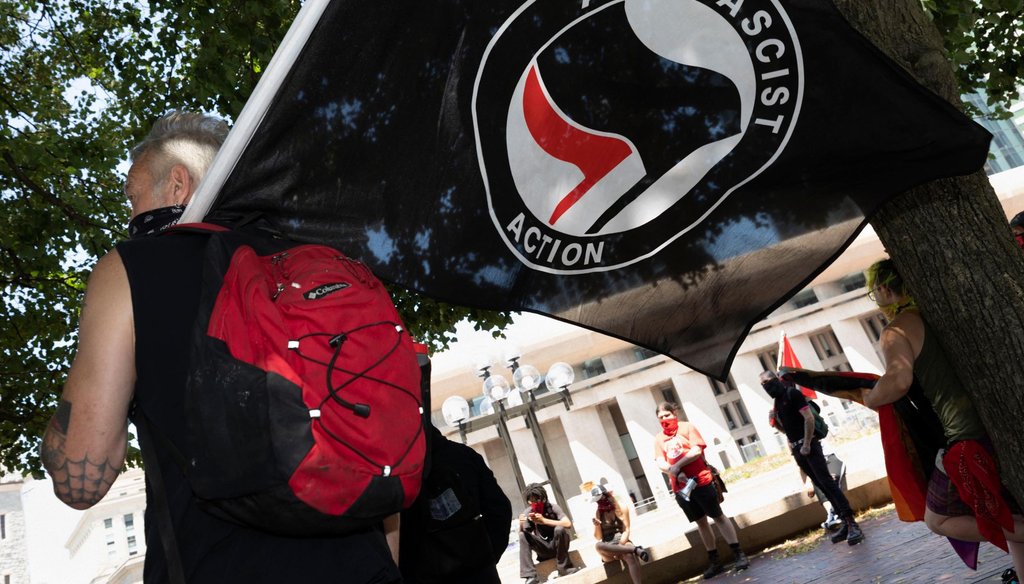 An anti-fascist protester holds a flag on the Christian Science Plaza on July 11, 2020, in Boston. (AP)