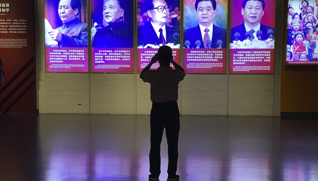 A visitor to a museum takes photos of the portraits of Chinese President Xi Jinping and his predecessors in Beijing on Sept. 27, 2022. (AP Photo/Ng Han Guan)