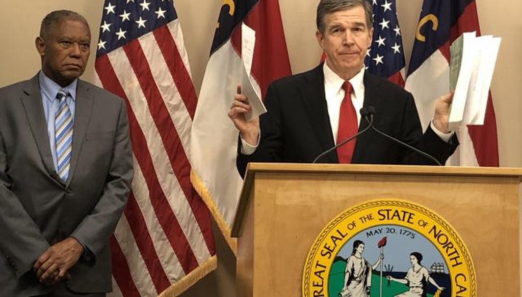 Gov. Roy Cooper holds the Republican budget in his left hand, his suggested changes in his right, as Senate Minority Leader Dan Blue looks on. (via WRAL)