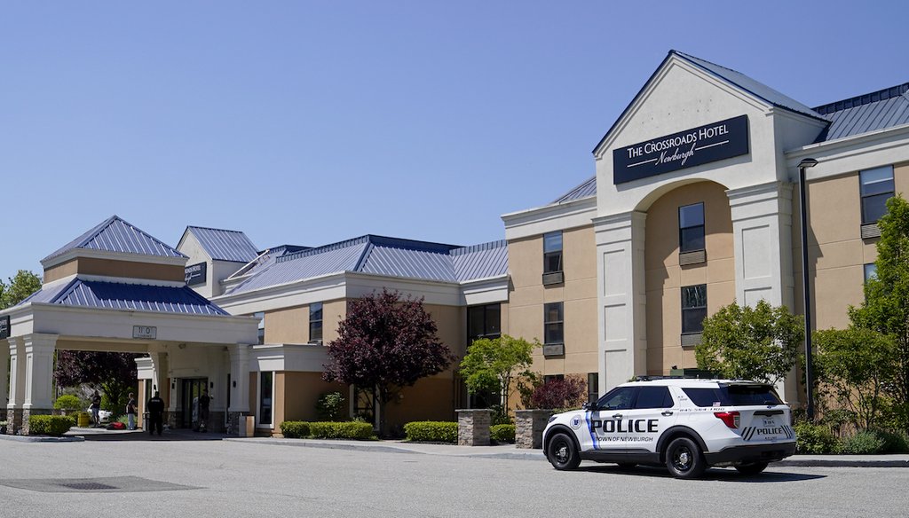 A Town of Newburgh, N.Y., police vehicle is parked outside as security and staff personnel mill about The Crossroads Hotel where two busloads of migrants arrived hours earlier May 11, 2023.