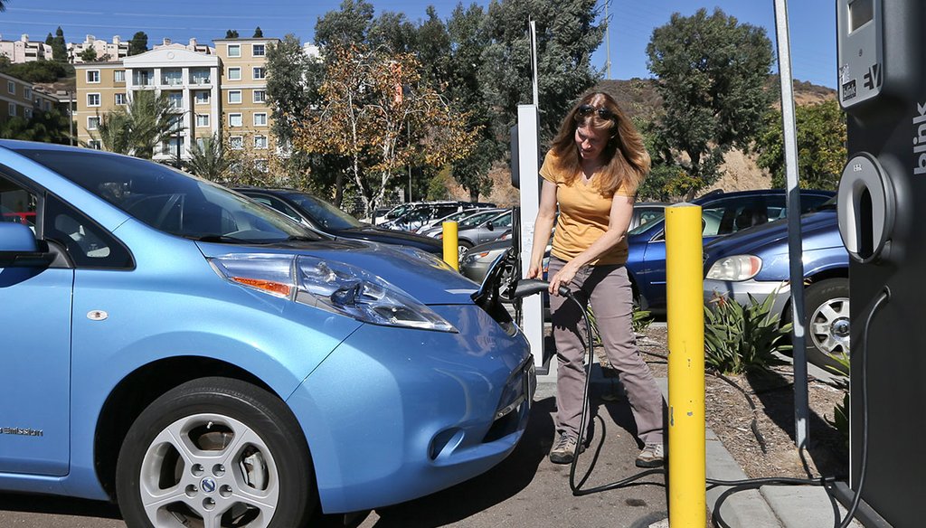 Angie Vorhies plugs in the charging cord to her Nissan Leaf electric vehicle at a mall Nov. 13, 2013, in San Diego. (Lenny Ignelzi/AP)