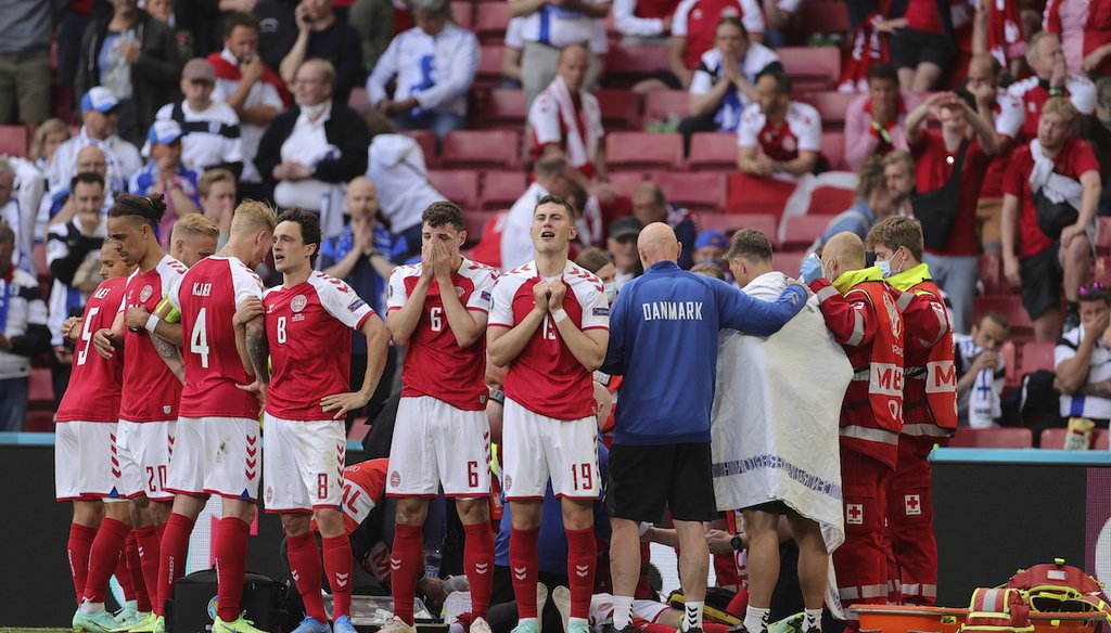 Denmark players react after the collapse of their teammate Christian Eriksen during the Euro 2020 soccer championship group B match between Denmark and Finland at Parken stadium in Copenhagen, Denmark, June 12, 2021. (AP)