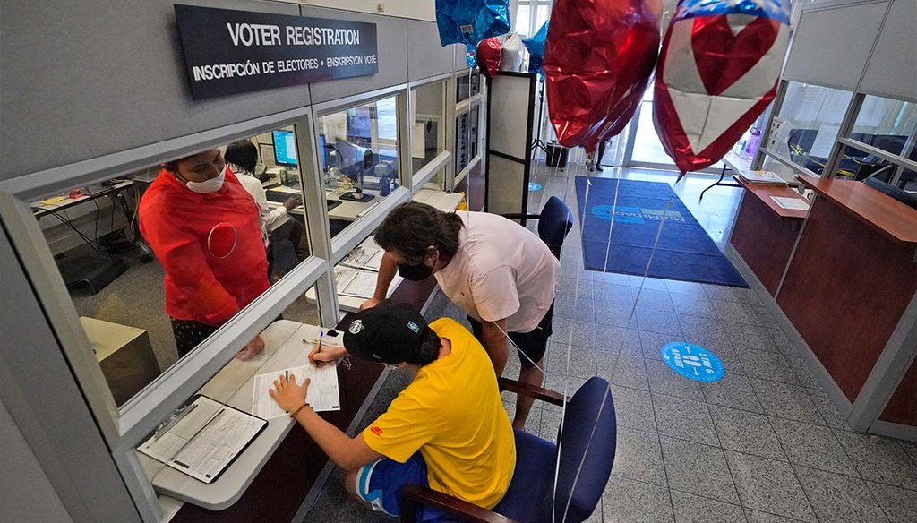 Lucas Saez, foreground, completes his voter registration form as his father, Ramiro Saez, center rear, watches Oct. 6, 2020, in Doral, Fla. (AP)