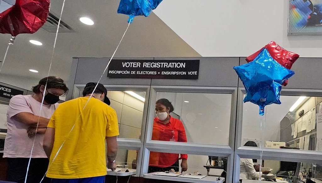 Lucas Saez turns in his voter registration form to temporary worker Loren Quiroz, center on Tuesday, Oct. 6, 2020, at the Miami-Dade County Elections Department in Doral, Fla. (AP)