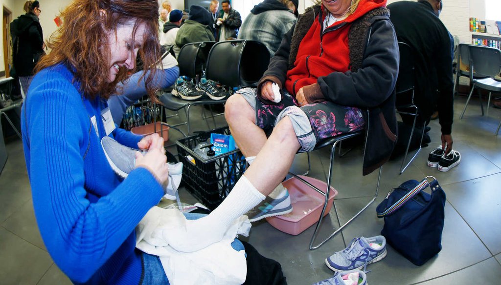 Volunteer Nicole Clark, left, laces new tennis shoes for Patricia Gingery after washing her feet at the Denver Rescue Mission Friday, April 3, 2015, in Denver. Care for the homeless was part of city's Easter celebration. (AP)