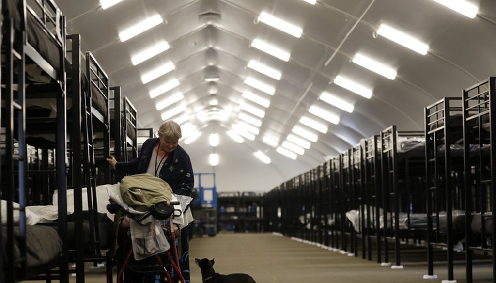 Verna Vasbinder prepares her new bunk in downtown San Diego's Temporary Bridge Shelter for the homeless in December 2017 as her dog, Lucy Lui, looks on. (AP Photo/Gregory Bull)
