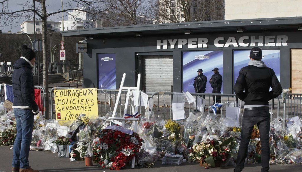 People look at flowers outside a kosher grocery store in Paris, where four people where killed in a terror attack Jan. 9. (AP Photo/Michel Euler)