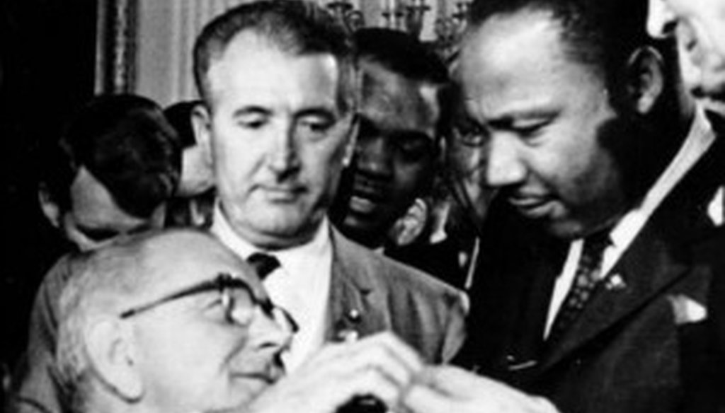 President Lyndon B. Johnson hands a pen to the Rev. Martin Luther King, Jr., during signing of the Civil Rights Act of 1964.