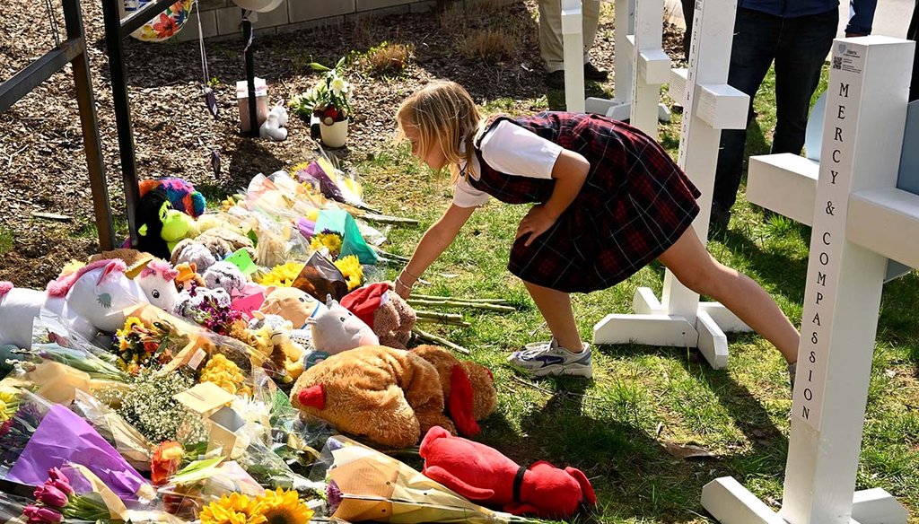 A young girl on March 28, 2023, places an item at a growing memorial for the victims of the shooting at the entry to The Covenant School in Nashville, Tenn. (AP)