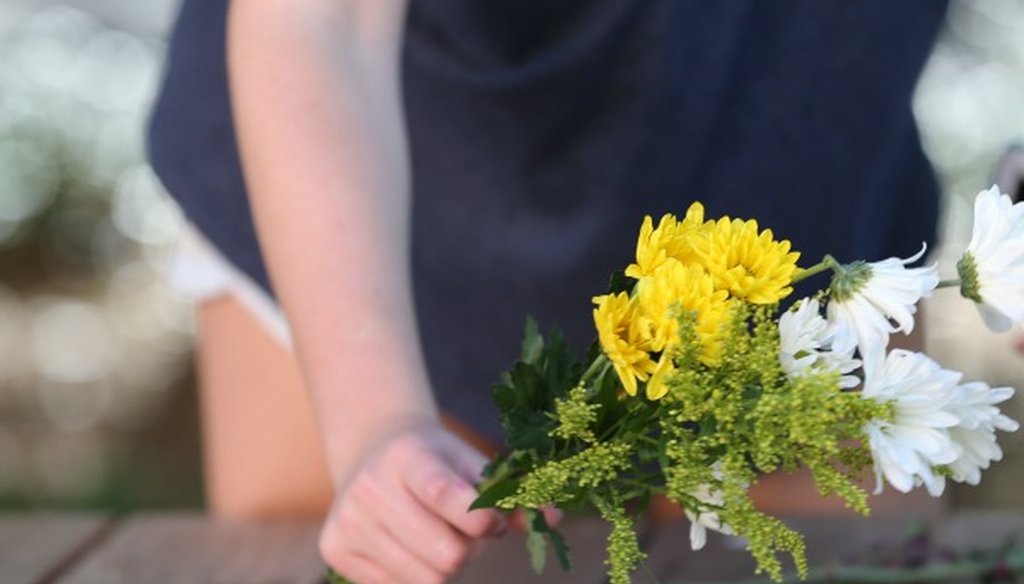 Students led by Montana Moore place flowers on the benches outside a University of Texas at Austin gym Tuesday May 2, 2017, as the campus tries for normalcy the day after a biology student knifed fellow students (Ralph Barrera, Austin American-Statesman).