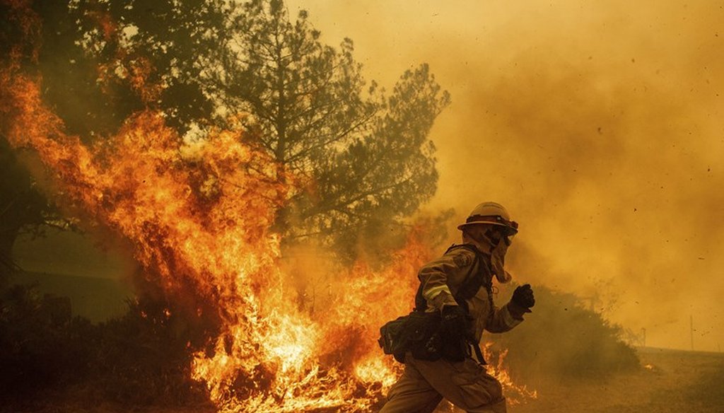 A firefighter runs while trying to save a home as a wildfire tears through Lakeport, Calif. on Tuesday, July 31, 2018. AP Photo / Noah Berger