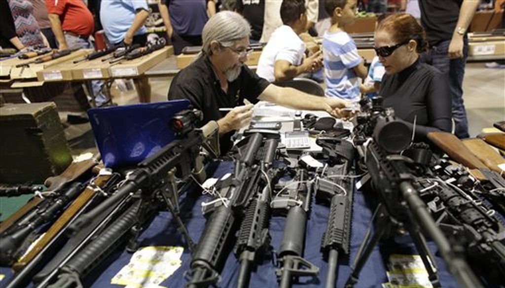 Harvey Kornnfield, owner of Airport Pawn, left, works on a sale with Bamula Schlesinger, right, at a gun show hosted by Florida Gun Shows, Saturday, Jan. 9, 2016, in Miami. Schlesinger purchased an Uzi and a Smith & Wesson 38. (AP)