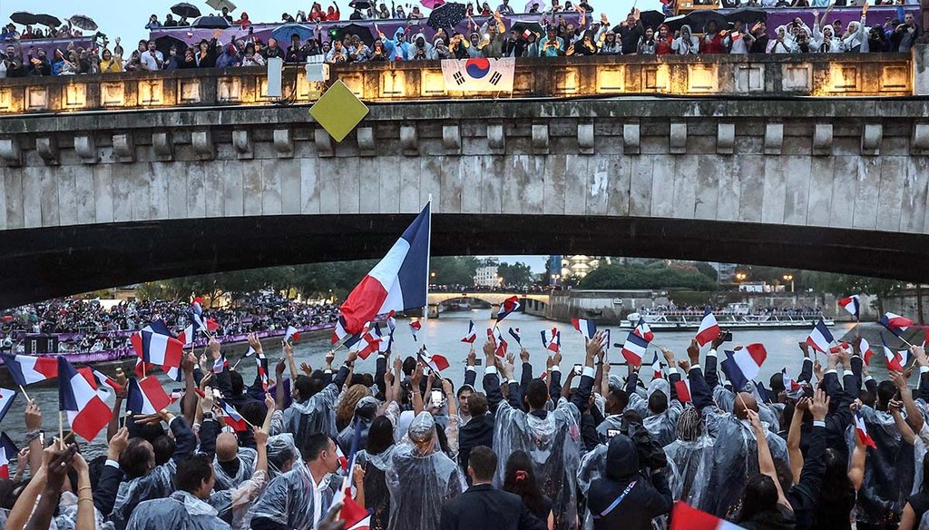 French athletes wave flags, July 26, 2024, as they sail in a boat on the Seine River during the opening ceremony for the Summer Olympics in Paris. (AP)