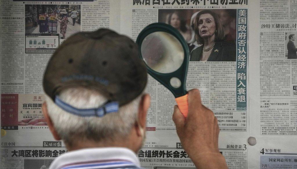 A man uses a magnifying glass to read a newspaper headline reporting on U.S. House Speaker Nancy Pelosi's Asia visit, at a stand in Beijing on July 31, 2022. (AP)