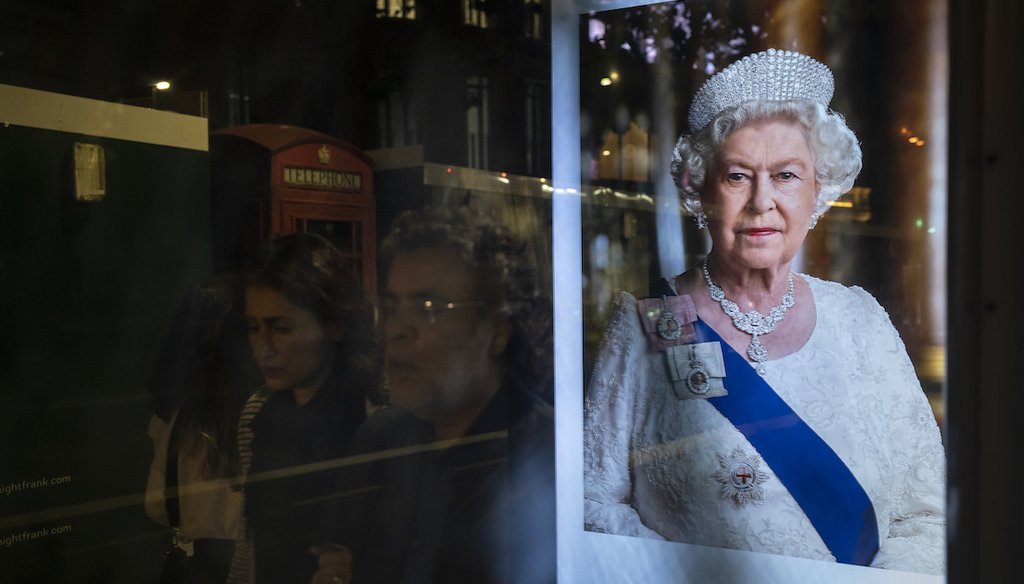 People walk past a photo of Queen Elizabeth II reflected on a bus stop in London, Sept. 9, 2022. (AP)