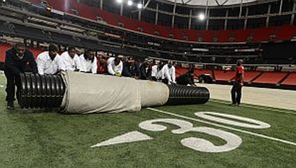 Work crews cover the playing field with a tarp in preparation for a Monster Truck event at the Georgia Dome earlier this month. Negotions are ongoing to replace the Dome with a proposed new $1 billion retractable-roof stadium.
