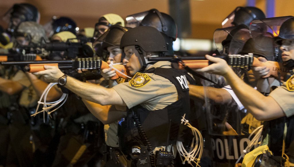 Police aim their weapons and make their way down West Florissant Avenue, pushing protesters north on the street in Ferguson, Mo., the night of Aug. 18, 2014. (New York Times)