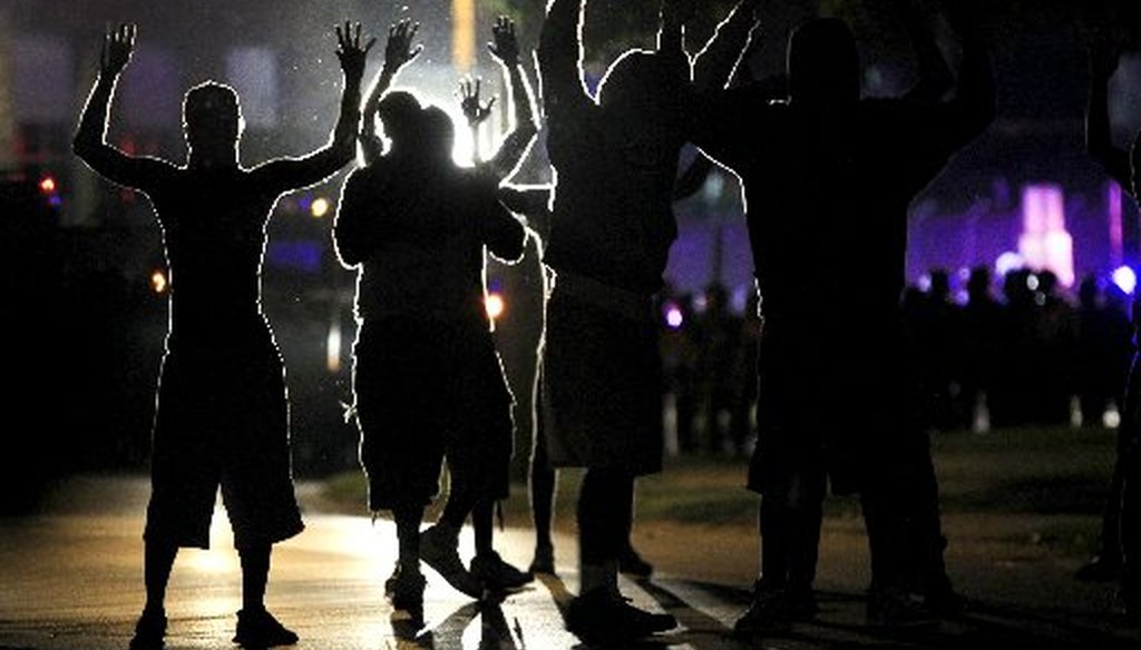 People raise their hands for advancing police wearing riot gear on Aug. 11, 2014 in Ferguson, Mo. Several nights of protests erupted in the suburb of St. Louis after a white police officer shot a black man named Michael Brown on Aug. 9. (AP photo)