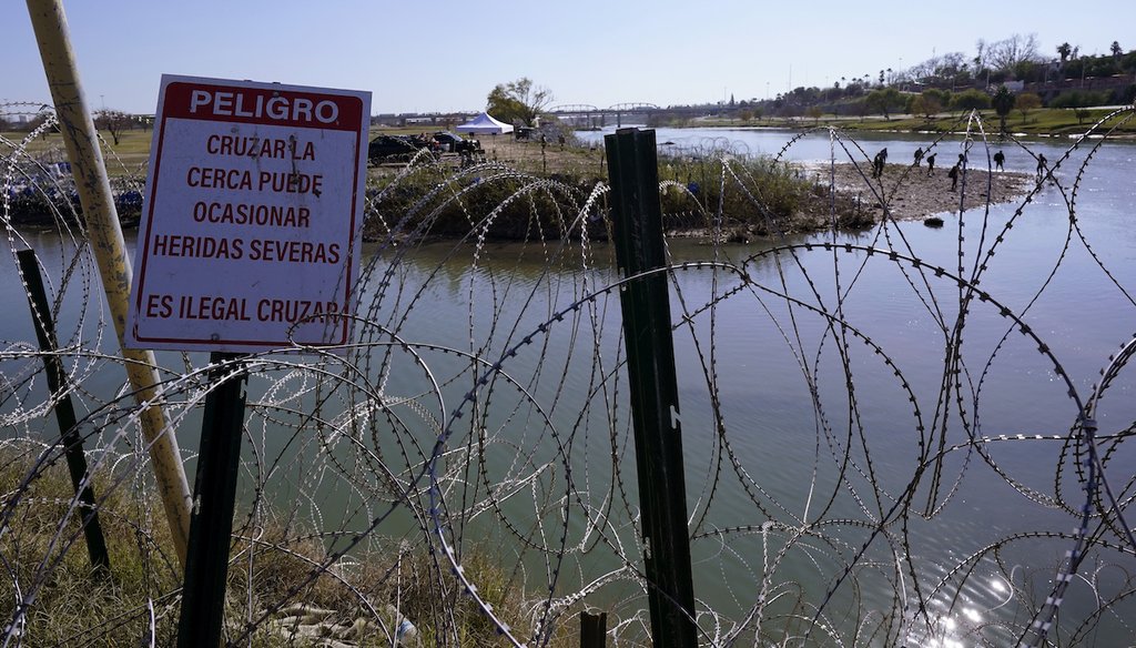 Migrants cross the Rio Grande into the U.S. from Mexico behind concertina wire and a sign warning that it's dangerous and illegal to cross on Jan. 3, 2024, in Eagle Pass, Texas. (AP)