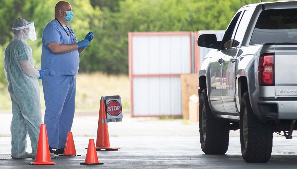 Health workers prepare to administer a COVID-19 test at a drive-through testing area in Central Texas (Ricardo Brazziell/Austin American-Statesman).