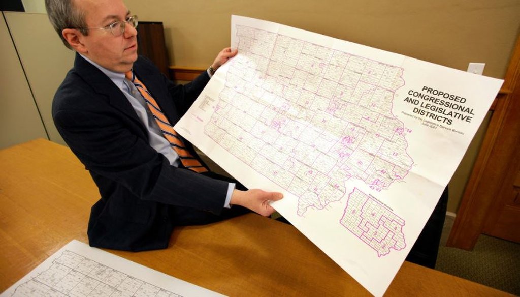 Ed Cook, legal counsel for the Iowa Legislative Services Agency, holds a map of Iowa that was used to help in drawing new congressional district lines in 2011. Three nonpartisan staffers draw district maps in Iowa. (AP Photo/Charlie Neibergall)