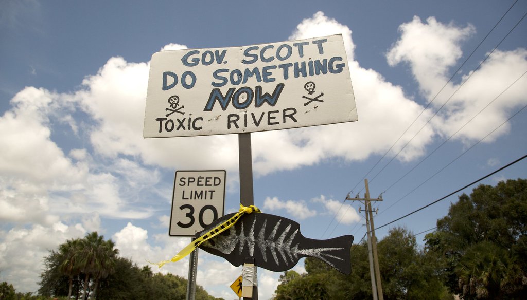 A protest sign greets Gov. Rick Scott and state Sen. Joe Negron before they tour part of the St. Lucie River near Stuart,Fla, Tuesday, Aug. 20, 2013, to access the environmental impact of water being released from Lake Okeechobee. (AP Photo/J Pat Carter)