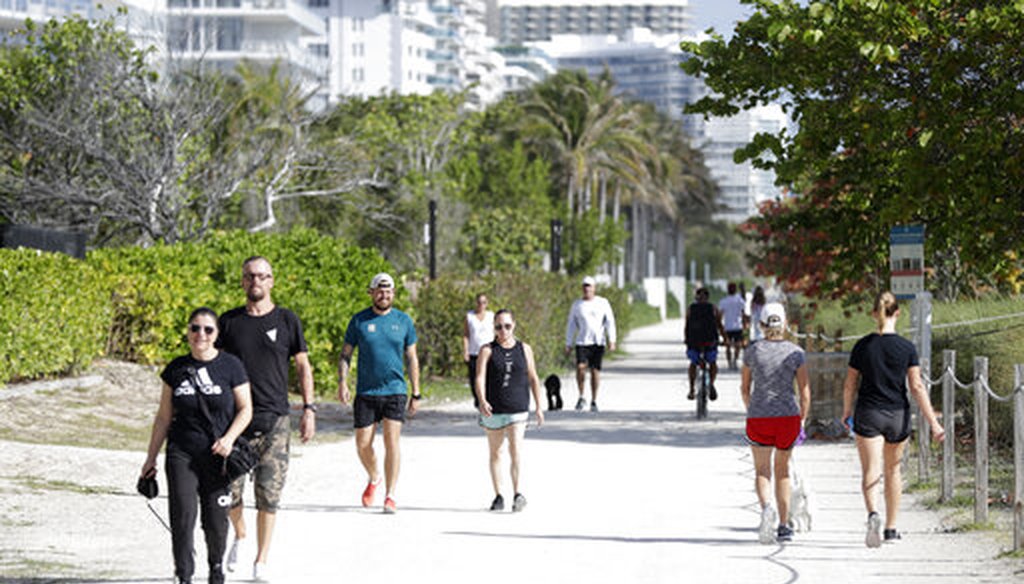 People walk their dogs and exercise on a hard-packed path along side the beach, Saturday, March 21, 2020, in Surfside, Fla. (AP)