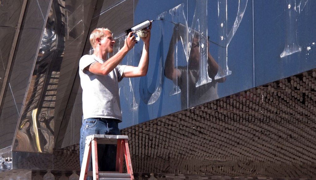 A worker applies caulk to holes in the facade of the former Trump Plaza casino in Atlantic City, N.J. after letters spelling out the casino's name were removed Oct. 6, 2014. (AP photo/Wayne Parry)