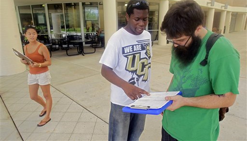 In this July 31, 2012, photo, Aubrey Marks, left, watches Jordan Allen, center, as he helps student Casey Eirhstaedt, right, register to vote at the University of Central Florida in Orlando, Fla. (AP)