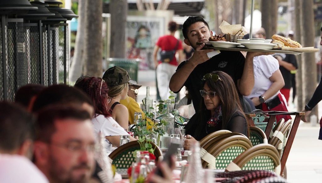 A waiter delivers food to patrons at a restaurant, Jan. 21, 2022, in Miami Beach, Fla. (AP)