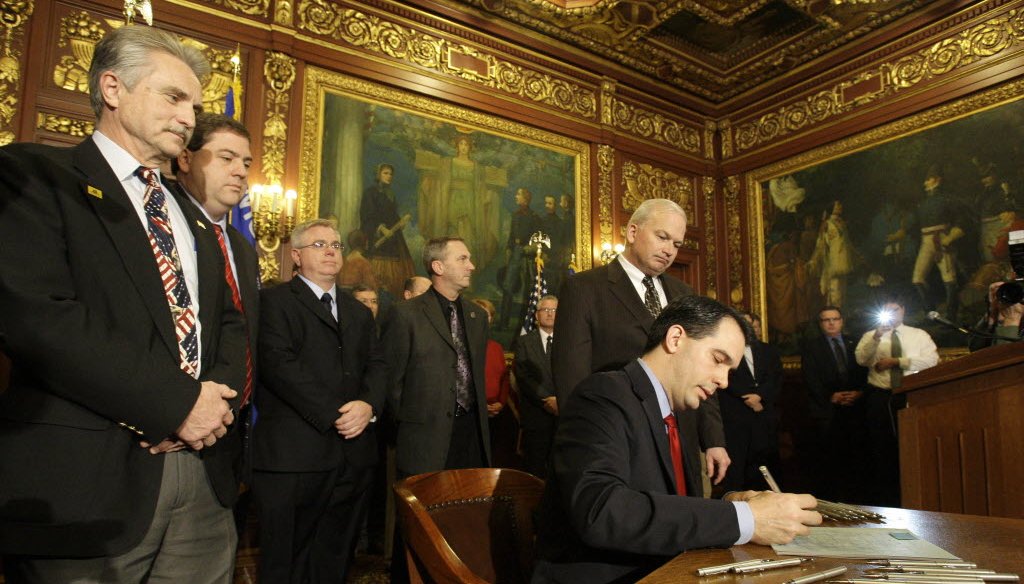 Wisconsin Gov. Scott Walker is surrounded by supporters March 12, 2011, as he signs Act 10 at the Wisconsin State Capitol. (Gary Porter/Milwaukee Journal Sentinel)