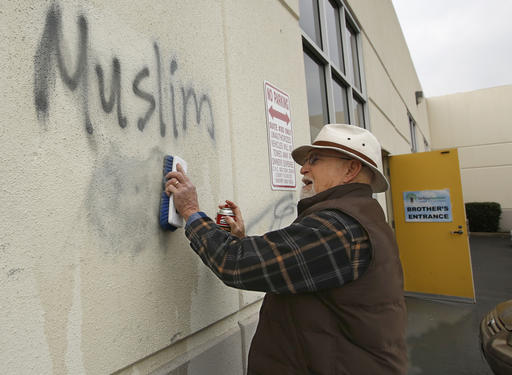 Tom Garing cleans up racist graffiti painted on the side of a mosque in what officials are calling an apparent hate crime, Wednesday, Feb. 1, 2017, in Roseville, Calif. (AP Photo/Rich Pedroncelli)