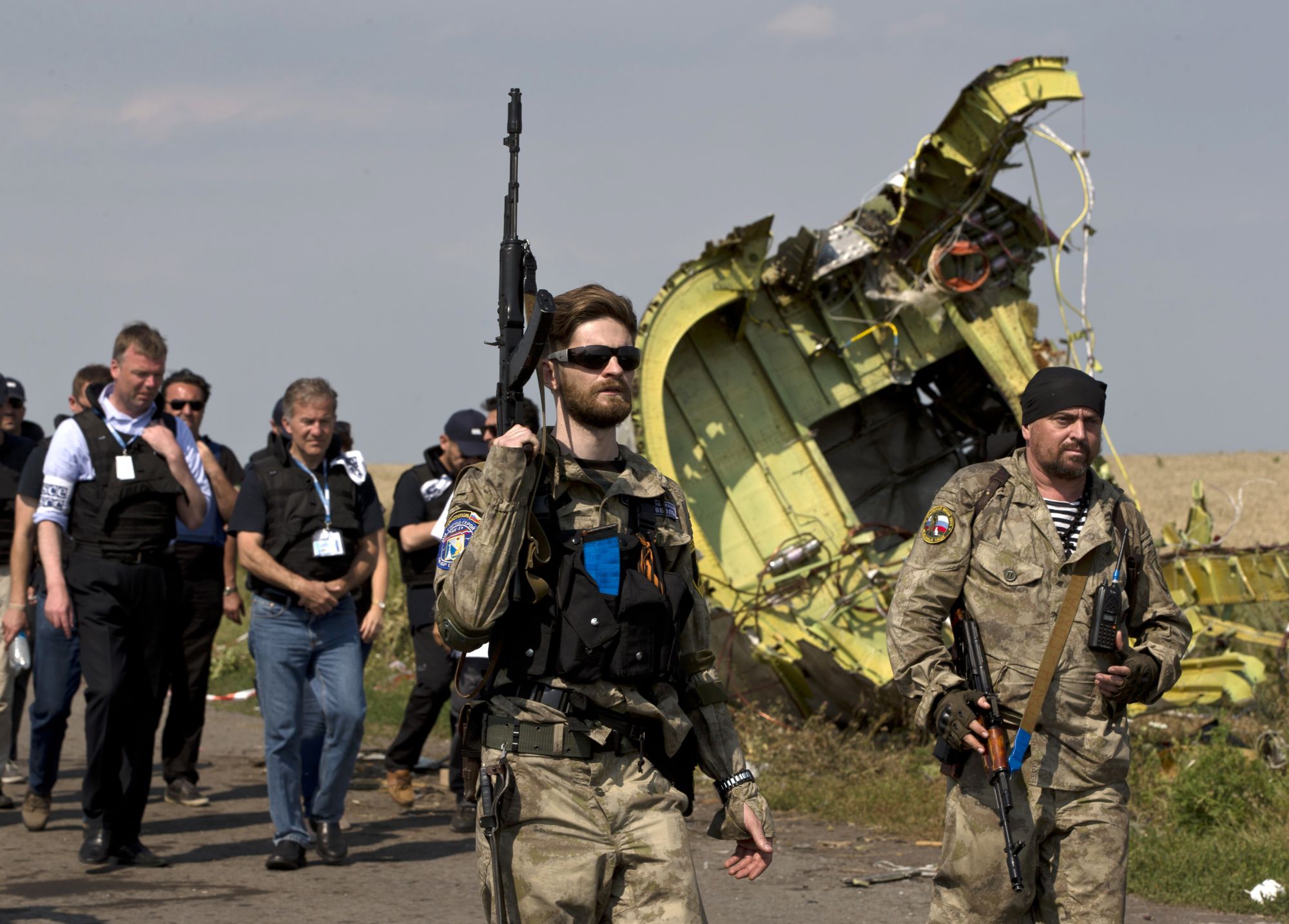 Pro-Russian rebels, right, walk by plane wreckage as they arrive for a media briefing at the crash site of Malaysia Airlines Flight 17 on July 22, 2014. (AP Photo)