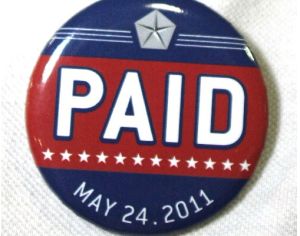 A Chrysler assembly line worker sports a pin labled "PAID" on his shirt before Chrysler Group announced the repayment of the remainder of its loans from the U.S. Government.