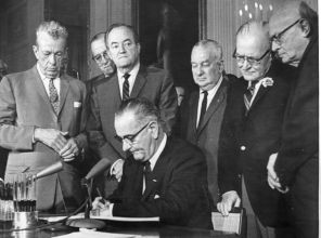 President Lyndon Johnson signs the Civil Rights Act. Also pictured are Sen. Everett Dirksen (left) and Reps. Charles Halleck and William McCulloch, all Republicans.