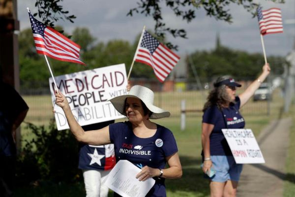 Protesters stand outside of a radio station where Sen. Ted Cruz, R-Texas, stopped for a radio interview on July 6, 2017, in advance of a town hall where a Republican health care bill was to be discussed. (AP/Eric Gay)