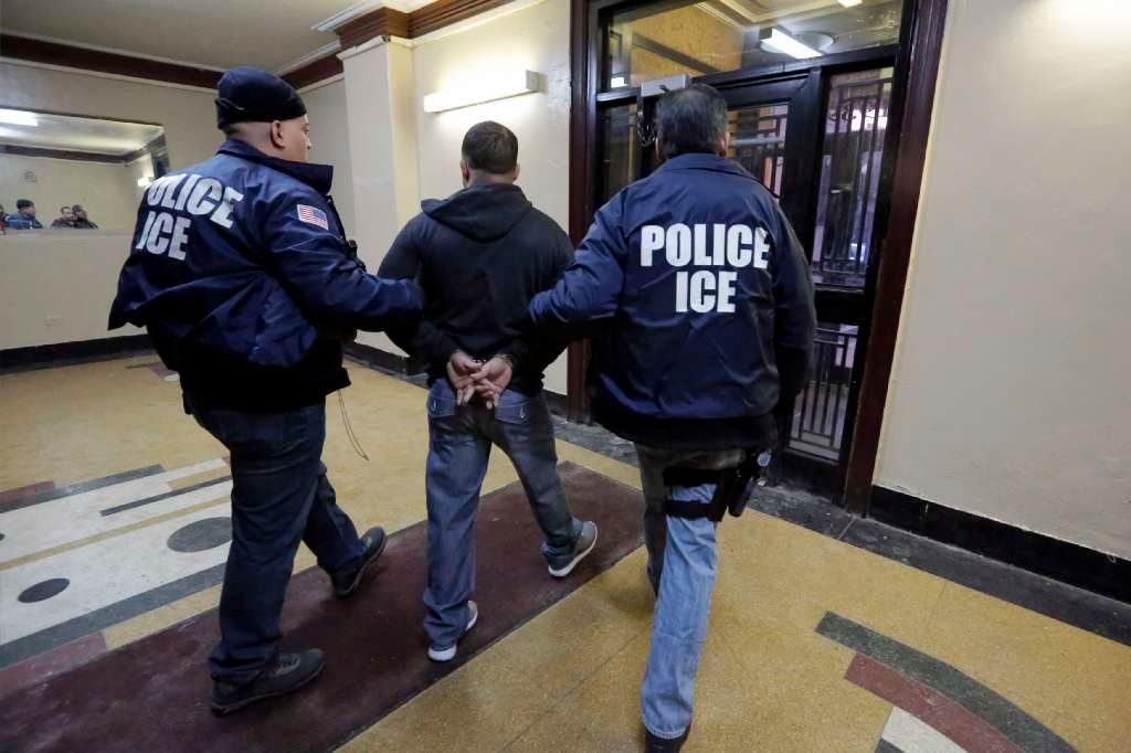 Immigration and Customs Enforcement officers escort an arrestee in an apartment building in the Bronx on March 3, 2015, during a series of early-morning raids. (AP/Richard Drew)