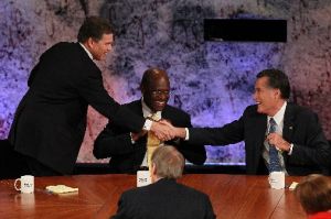 As Herman Cain looks on, Rick Perry and Mitt Romney shake hands at the conclusion of the Republican Presidential debate at Dartmouth College in Hanover, N.H.