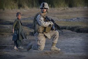 An Afghan boy stands next to a United States Marine during an operation in the volatile Helmand province of southern Afghanistan. For most Americans, a war like the one in Afghanistan tests the traditional boundaries of wartime and peacetime.