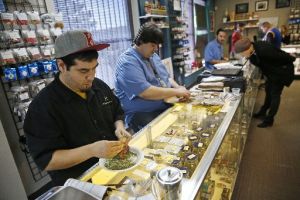 Employees roll joints behind the sales counter at Medicine Man marijuana dispensary in Denver, Colo. Recreational pot became legal this year. (AP)