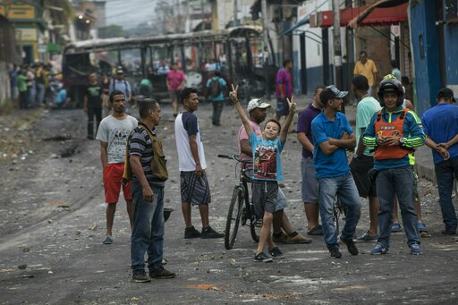 Residents gather in the streets where a public bus was burned during clashes between Bolivarian National Guards and anti-government protesters in Urena, Venezuela, near the border with Colombia, Sunday, Feb. 24, 2019. (AP)