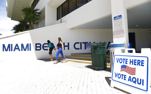 Pedestrians walk past a sign for a polling station at Miami Beach City Hall, Monday, Aug. 13, 2018, in Miami Beach, Fla. (AP)